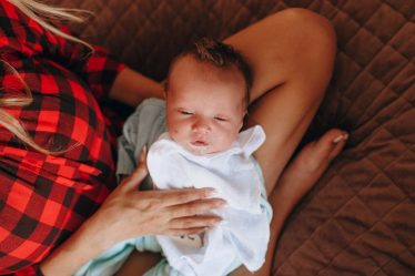 woman in red and black plaid shirt carrying baby in blue onesie