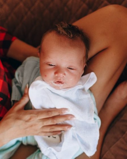 woman in red and black plaid shirt carrying baby in blue onesie