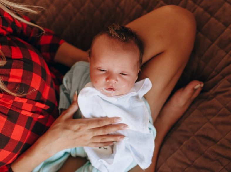 woman in red and black plaid shirt carrying baby in blue onesie