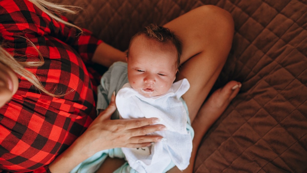 woman in red and black plaid shirt carrying baby in blue onesie